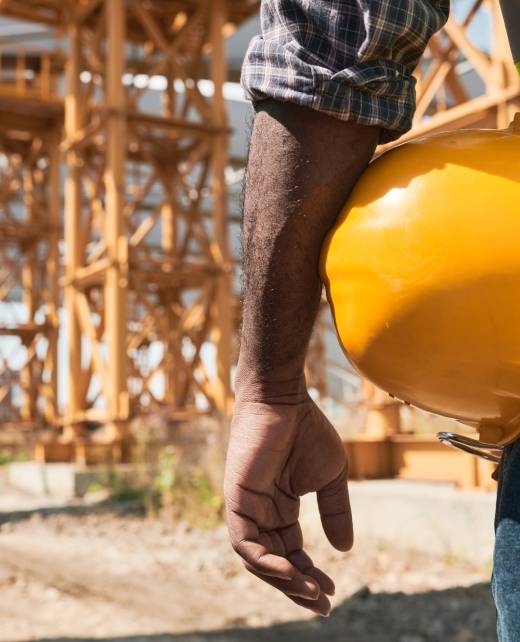 Building worker analyzing project plan Building worker analyzing project plan and discussing blueprint while standing on construction site
